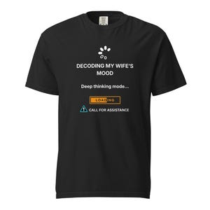 May include: Black t-shirt featuring white text and graphics. The text says "DECODING MY WIFE'S MOOD" above "Deep thinking mode..." and a loading bar graphic. Below is a call for assistance icon.