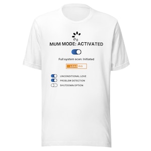 May include: White t-shirt with the text "MUM MODE: ACTIVATED" and a graphic resembling a system interface. Below the text are the words "Full system scan: Initiated" and "LOADING". Additional text includes "UNCONDITIONAL LOVE", "PROBLEM DETECTION", and "SHUTDOWN OPTION".