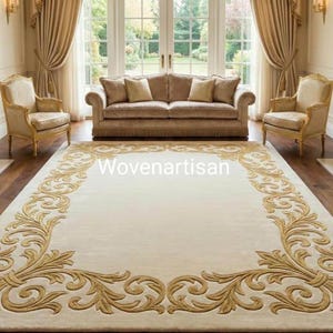May include: A large, rectangular ivory rug with an ornate gold floral border. The rug is centered in a luxurious living room with a sofa, chairs, and a fireplace. The text "Wovenartisan" is visible on the rug.