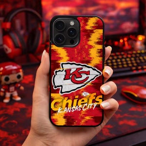 May include: A black phone case featuring the Kansas City Chiefs logo. The case has a red and yellow background with the team's logo and the words "Chiefs Kansas City" in white and yellow.
