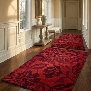 Puede incluir: Dos alfombras rojas con estampado floral sobre un suelo de madera noble en un pasillo. Las alfombras tienen un dise&ntilde;o floral rojo oscuro sobre un fondo rojo m&aacute;s claro. El pasillo tiene paredes color crema y molduras blancas.
