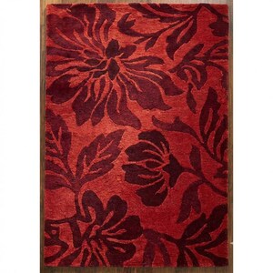 Puede incluir: Una alfombra rectangular roja con un estampado floral en un tono m&aacute;s oscuro de rojo. La alfombra presenta grandes flores y hojas estilizadas, creando un dise&ntilde;o audaz y decorativo. La alfombra est&aacute; colocada sobre un suelo de madera.