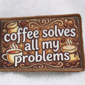 May include: A rectangular patch with a brown border and a coffee-themed design. The text "coffee solves all my problems" is displayed in white, with coffee beans and coffee cups illustrated around the text.