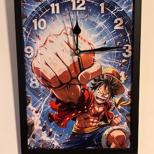 May include: A framed wall clock featuring a vibrant illustration of a manga character in action. The clock face is a blue and white design with black hands. The character is wearing a red jacket and straw hat, with the text "ONE PIECE" at the bottom.