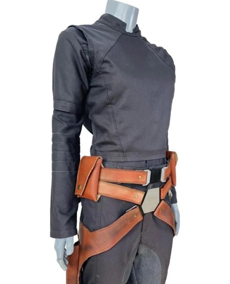 May include: A dark charcoal long-sleeved top with a high collar and matching trousers, paired with a tan leather utility belt featuring multiple pouches, a central metallic hexagonal buckle, and integrated leg straps with brass-colored hardware.