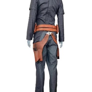May include: A dark gray long-sleeved jacket and matching trousers paired with a tan leather utility belt. The belt features a prominent holster attachment on the right side, secured with metallic hardware, worn over the dark gray fabric ensemble.