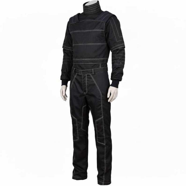 Op de afbeelding: Een zwarte jumpsuit met lange mouwen, een hoge opstaande kraag, gestructureerde schouderpanelen en opvallende witte contraststiksels op het lijfje, de mouwen en de broekspijpen. Het kledingstuk heeft een getailleerde pasvorm en rechte broekspijpen.