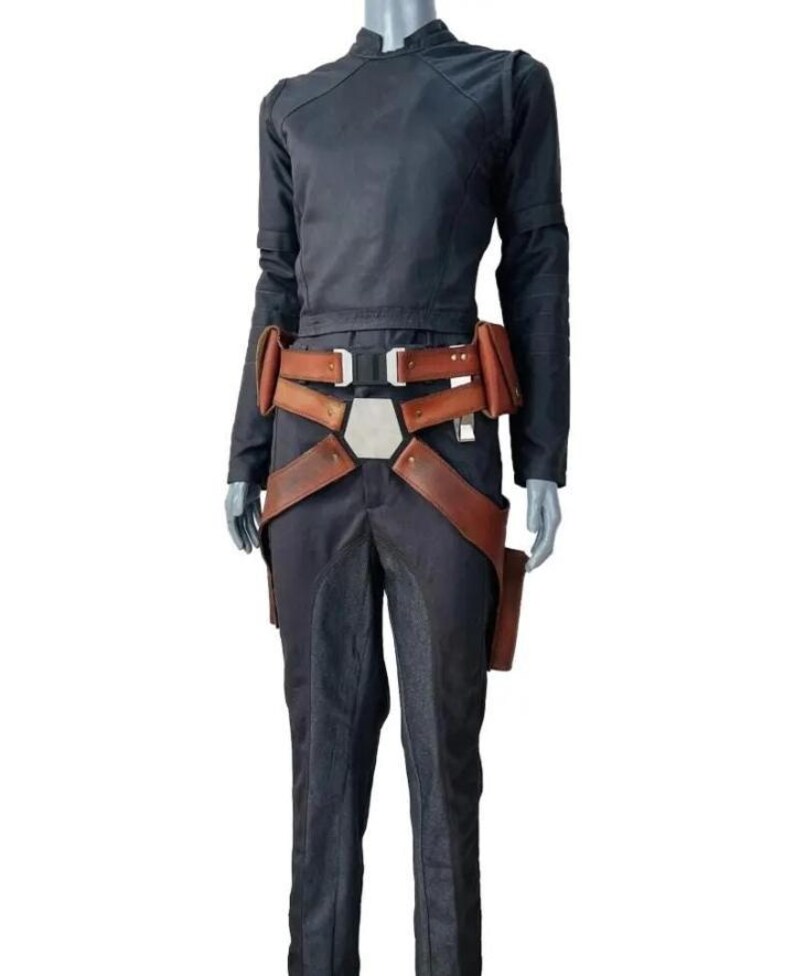 May include: A dark charcoal gray long-sleeved jumpsuit with a high collar, paired with a brown leather utility belt featuring multiple pouches, a central silver-toned pentagonal buckle, and adjustable straps that extend down the hips.