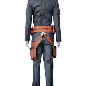 May include: A dark gray long-sleeved shirt and matching trousers paired with a tan leather utility belt. The belt features a wide waistband and two holster-like pouches hanging down the sides, secured with a silver-toned metal buckle at the front.