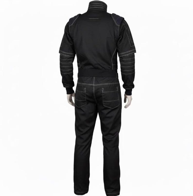 Op de afbeelding: Een zwarte jumpsuit met een hoge kraag, lange mouwen met geribbelde boorden en zichtbare witte contraststiksels. Het kledingstuk is voorzien van schouderpanelen, een getailleerde tailleband en twee achterzakken, weergegeven vanaf de achterkant.