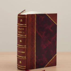 K&ouml;nnte beinhalten: Ein Hardcover-Buch mit dem Titel "Pistis Sophia" mit einem weinroten Ledereinband und goldenen Akzenten. Der Buchr&uuml;cken zeigt den Titel und den Namen des Autors in goldener Schrift. Ein rotes Leseband ragt aus den Seiten.