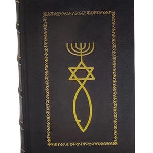 Puede incluir: Un libro de tapa dura con una cubierta oscura que presenta s&iacute;mbolos religiosos dorados: una Estrella de David, una menor&aacute; y un pez. La cubierta tiene un borde dorado decorativo. El lomo es texturizado. El libro es nuevo.