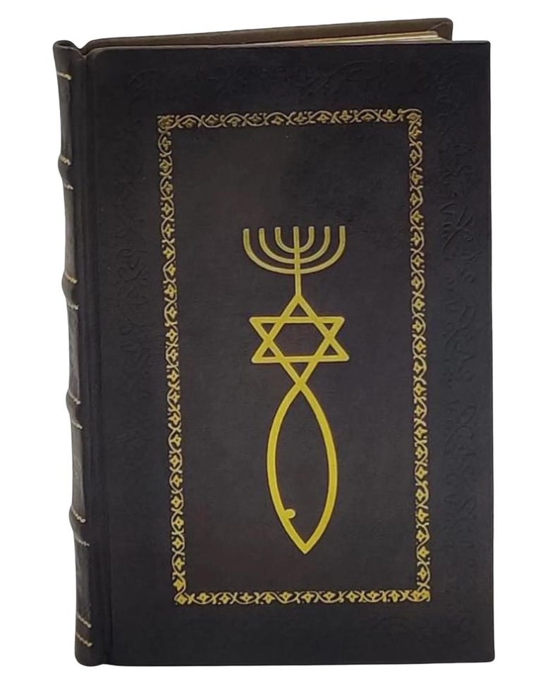 Puede incluir: Un libro de tapa dura con una cubierta oscura que presenta s&iacute;mbolos religiosos dorados: una Estrella de David, una menor&aacute; y un pez. La cubierta tiene un borde dorado decorativo. El lomo es texturizado. El libro es nuevo.