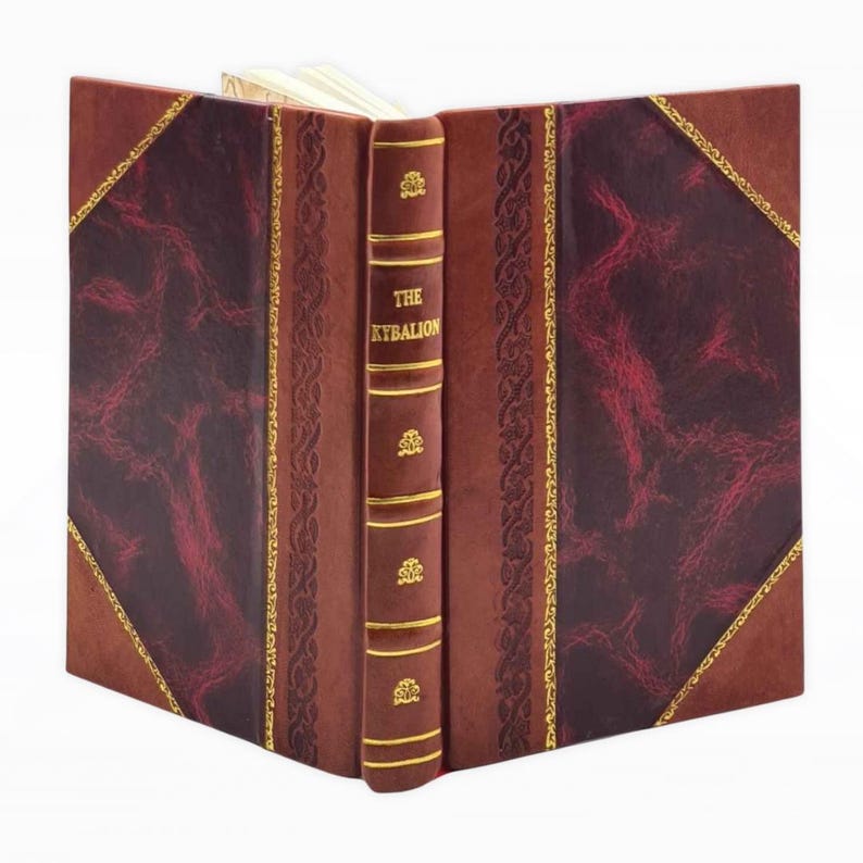 May include: A hardcover book titled "The Kybalion" with a brown leather cover. The cover features burgundy diamond-shaped panels with a textured pattern, gold trim, and decorative accents. The spine is also brown with gold lettering and embellishments.
