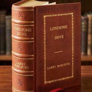 May include: A hardcover book titled "Lonesome Dove" by Larry McMurtry. The book has a brown leather cover with gold lettering and decorative accents. A red ribbon bookmark is visible.
