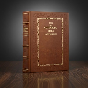 Può includere: Un libro rilegato in pelle marrone, la Bibbia di Gutenberg, è in posizione verticale. La copertina presenta scritte dorate e bordi decorativi. Anche il dorso ha scritte dorate. Il libro è su una superficie di legno.