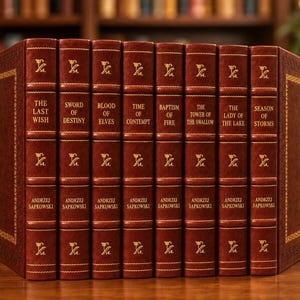 Puede incluir: Un conjunto de ocho libros de tapa dura de Andrzej Sapkowski con cubiertas de color rojo oscuro tipo cuero, letras doradas en relieve y motivos florales decorativos en los lomos. Los títulos incluyen The Last Wish, Sword of Destiny y otros.