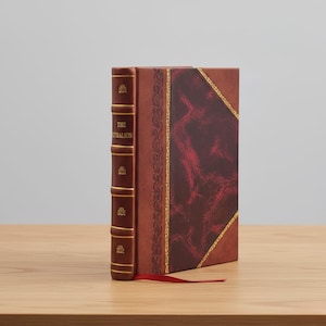May include: A hardcover book titled "The Kybalion" with a brown leather cover and gold accents. The spine is a darker brown with gold lettering and decorative elements. A red ribbon bookmark extends from the book.