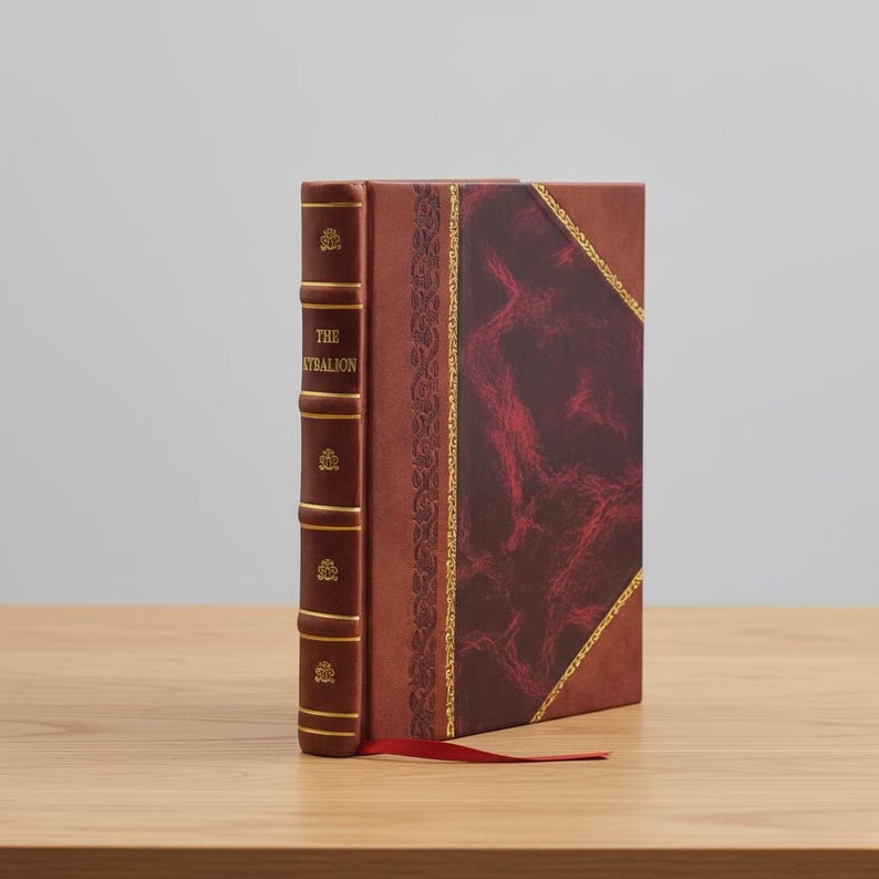 May include: A hardcover book titled "The Kybalion" with a brown leather cover and gold accents. The spine is a darker brown with gold lettering and decorative elements. A red ribbon bookmark extends from the book.