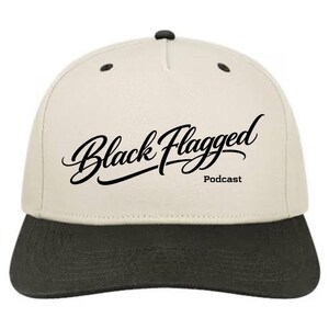 May include: A baseball cap with a cream-coloured crown and a dark grey brim. The cap features the text "Black Flagged Podcast" in a stylish, cursive font. The cap has a classic, structured design.