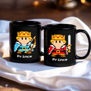 May include: Two black ceramic mugs with pixelated illustrations of a prince. One prince wears blue and holds a bow and arrow, the other wears red and holds a sword. The word "Prince" is printed below each image.