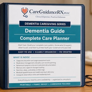May include: A navy blue binder titled "Dementia Guide Complete Care Planner" with the CareGuidanceRN logo. The binder includes a list of contents and is designed for caregivers. A pair of eyeglasses rests on the wooden surface.