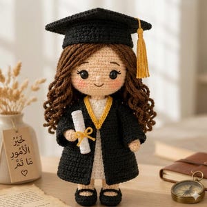 Peut inclure: Une poupée crochetée aux longs cheveux bruns portant une toque de diplômé noire avec un pompon jaune et une toge noire sur une robe blanche. La poupée tient un petit diplôme blanc crocheté noué d'un ruban jaune et porte des chaussures noires.