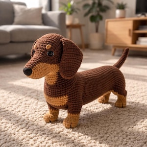 Peut inclure: Un jouet teckel au crochet avec un corps marron foncé et des accents beige clair sur le poitrail, le museau et les pattes. L'animal en peluche possède des yeux en plastique noir, un nez noir et de longues oreilles tombantes en maille.