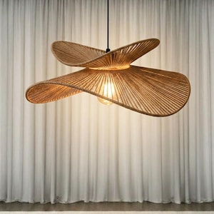 May include: A hanging pendant light fixture featuring a wide, layered shade constructed from thin, light brown woven fibers. The shade has a distinct, undulating, wave-like shape with a central light bulb emitting a warm, soft glow.