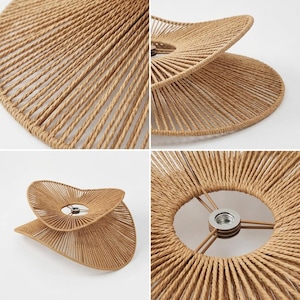 May include: A light brown lamp shade constructed from tightly wound rope arranged in a radial pattern. The shade features a dual-layered, wavy, organic shape with a central metal socket mount supported by three thin metal spokes at the center.