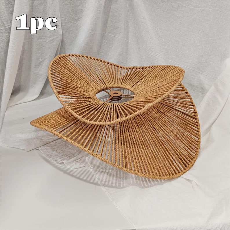 May include: A tan, woven rope lampshade with a wide, asymmetrical, wavy-edged design. The structure features a central circular metal frame with a light brown finish. The text '1pc' is visible in the upper left corner of the image.