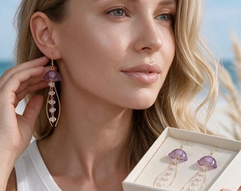 May include: A pair of drop earrings featuring a translucent purple dome-shaped top resembling a jellyfish bell, with gold-toned wire accents and a central strand of small, clear, faceted beads hanging down from the centre of the dome.