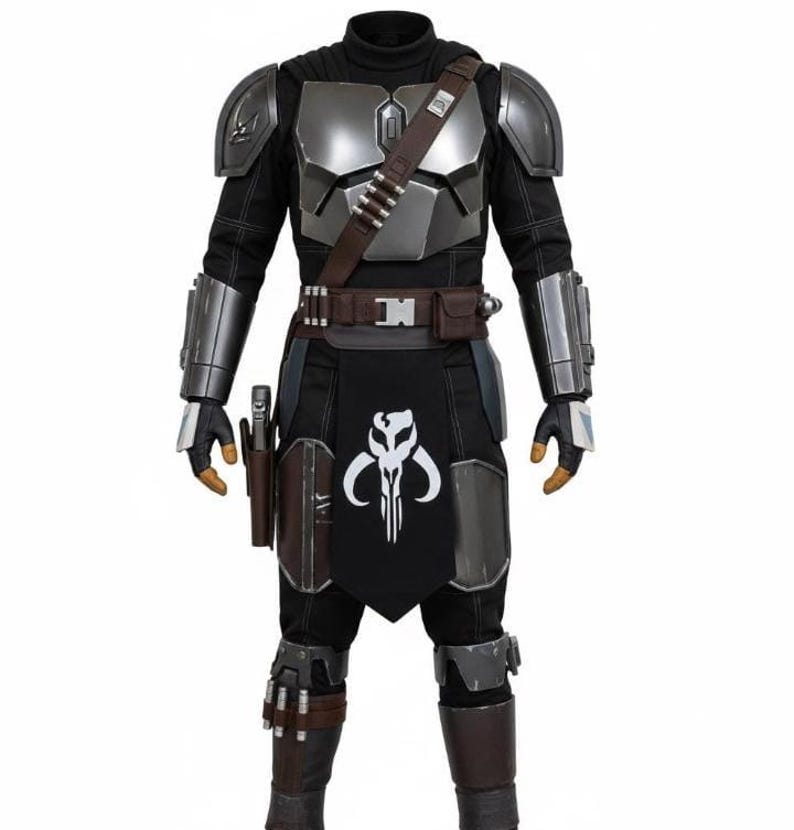 K&ouml;nnte beinhalten: Ein Ganzk&ouml;rperkost&uuml;m in Schwarz und Silber. Das Outfit umfasst einen schwarzen Rollkragenpullover, silberne Panzerplatten, einen braunen G&uuml;rtel mit Taschen und eine schwarze Sch&uuml;rze mit einem wei&szlig;en Totenkopf-Emblem. Die Handschuhe und Stiefel sind braun.