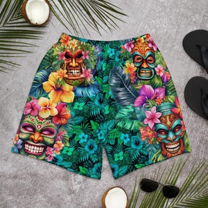 Könnte beinhalten: Hawaiianische Shorts mit farbenfrohen Tiki-Masken-Designs und tropischen Blumen. Die Shorts zeigen einen üppigen grünen Hintergrund mit Hibiskus, Palmenblättern und anderen floralen Elementen. Bequeme Passform für warmes Wetter.