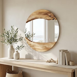 Pu&ograve; includere: Uno specchio rotondo con una cornice in legno naturale &egrave; appeso sopra una consolle in legno. La cornice dello specchio ha una forma organica unica. Il tavolo &egrave; decorato con vasi di verde, libri e un piccolo cestino intrecciato.
