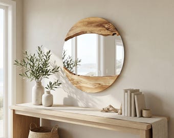 May include: A circular mirror with a natural wood frame is displayed above a wooden console table. The mirror's frame has an organic shape. The table is decorated with vases of greenery, books, and a small woven basket.