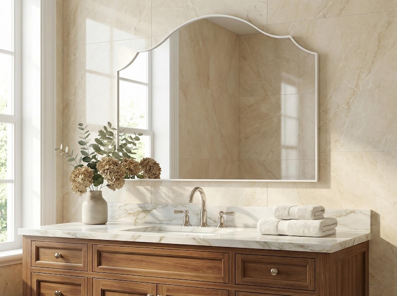 Peut inclure: Un meuble-lavabo de salle de bain avec un grand miroir cintr&eacute;. Le meuble est en bois fonc&eacute; et poss&egrave;de un comptoir en marbre. Un vase de fleurs et des serviettes blanches pli&eacute;es sont pos&eacute;s sur le comptoir. Le miroir a un cadre blanc.