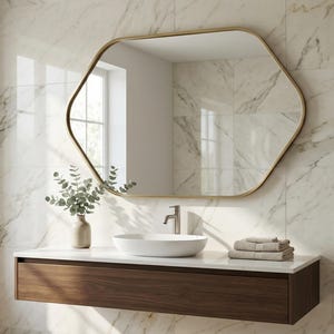 May include: A modern bathroom vanity with a hexagonal gold-framed mirror. The vanity features a white countertop, a white oval sink, and a dark wood cabinet. A vase with greenery and a stack of towels are also present.