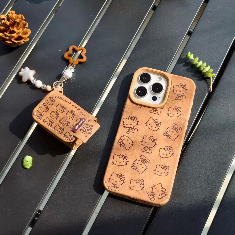 Peut inclure: Un &eacute;tui de t&eacute;l&eacute;phone et un portefeuille beiges avec un motif Hello Kitty r&eacute;p&eacute;t&eacute;. L'&eacute;tui de t&eacute;l&eacute;phone a une d&eacute;coupe pour l'appareil photo et un bord clair. Le portefeuille porte l'inscription "HELLO KITTY" et un charm.