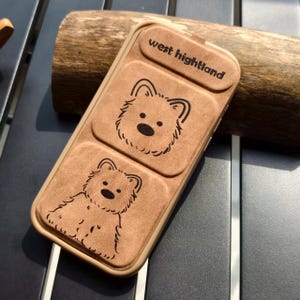 May include: A tan phone case with a bear design. The case has a rectangular shape with rounded corners and a flip-up top. The text "west hightland" is printed on the top flap. Two bear illustrations are on the front.