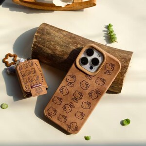 Peut inclure: Coque de t&eacute;l&eacute;phone marron et porte-cl&eacute;s assorti avec un motif Hello Kitty r&eacute;p&eacute;t&eacute;. L'&eacute;tui du t&eacute;l&eacute;phone a un bord marron clair autour de l'appareil photo. Le porte-cl&eacute;s comprend un charm en forme d'&eacute;toile et un petit &eacute;tui avec l'inscription "Hello Kitty".