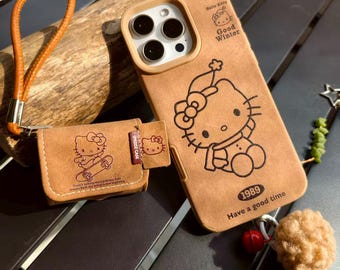 Niedliches Vintage-Set mit passender iPhone- und AirPods-Hülle im Cartoon-Katzen-Design – Retro-Technik-Bundle aus braunem Leder mit Handschlaufe und Bommelanhänger, ein charmantes Geschenk