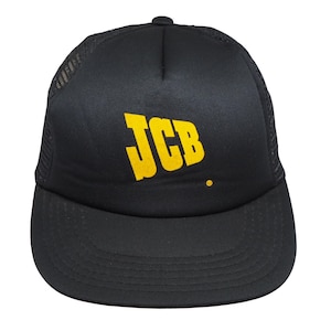 Può includere: Cappellino da camionista nero con visiera curva e retro in rete. La parte anteriore presenta le lettere gialle "JCB" in grassetto, con un piccolo punto giallo sotto.