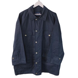 Peut inclure: Une veste bleu marine foncé dotée d'un col classique, d'une patte de boutonnage avant avec des fermetures à pression métalliques et de deux grandes poches à rabat sur la poitrine. Les manches longues ont des poignets réglables à pression.