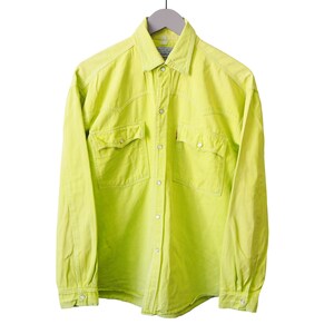May include: A bright yellow long-sleeved shirt with two chest pockets and button fastenings. The shirt is suspended from a grey hanger against a white backdrop. It features a classic collar and buttoned cuffs.