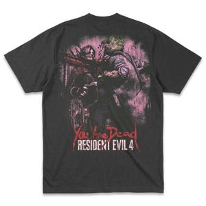 Może przedstawiać: Ciemnoszara koszulka z grafiką z Resident Evil 4. Projekt przedstawia brutalną scenę z dwiema postaciami, słowami "You Are Dead" i "Resident Evil 4" w kolorze czerwonym. Obraz ma postarzany wygląd.