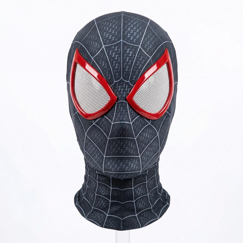 Puede incluir: Una m&aacute;scara negra de Spider-Man con un dise&ntilde;o de telara&ntilde;a y aberturas para los ojos con bordes rojos. Las aberturas de los ojos tienen una malla blanca. La m&aacute;scara cubre toda la cabeza y el cuello, sobre un fondo blanco.