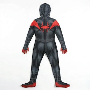 Puede incluir: Un disfraz de superh&eacute;roe negro y rojo con capucha. El disfraz presenta un emblema de ara&ntilde;a en la espalda y detalles rojos en los hombros, manos y pies. El traje tiene un patr&oacute;n texturizado.