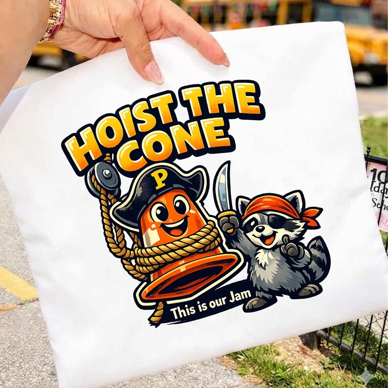 Peut inclure: Taie d'oreiller blanche avec un dessin anim&eacute; d'un c&ocirc;ne de signalisation pirate et d'un raton laveur pirate, avec le texte "HOIST THE CONE" et "This is our Jam". Le c&ocirc;ne est orange et le raton laveur est gris.