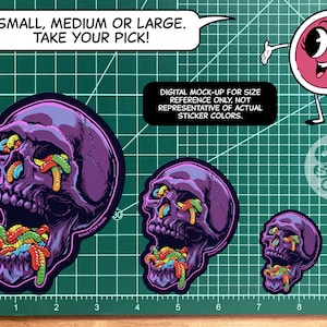 May include: Three different sizes of a sticker featuring a purple skull with colorful gummy worms coming out of its mouth and eyes. The text "SMALL, MEDIUM OR LARGE. TAKE YOUR PICK!" is at the top of the image. The text "DIGITAL MOCK-UP FOR SIZE REFERENCE ONLY, NOT REPRESENTATIVE OF ACTUAL STICKER COLORS." is in the middle of the image. The text "GIKR STUDIO .COM" is at the bottom of the image.